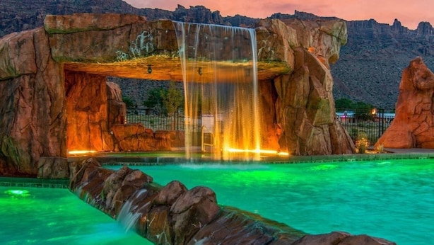 Una cascada con una piscina frente a formaciones rocosas.