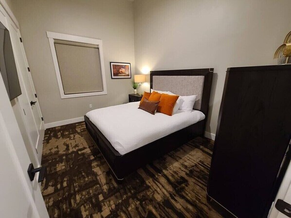 A hotel room with a large bed, a window with blinds, a nightstand with a lamp, and a dark-colored wardrobe. - SageCreek Resort D9- FieryFurnace - Top Rated Pool (Moab)