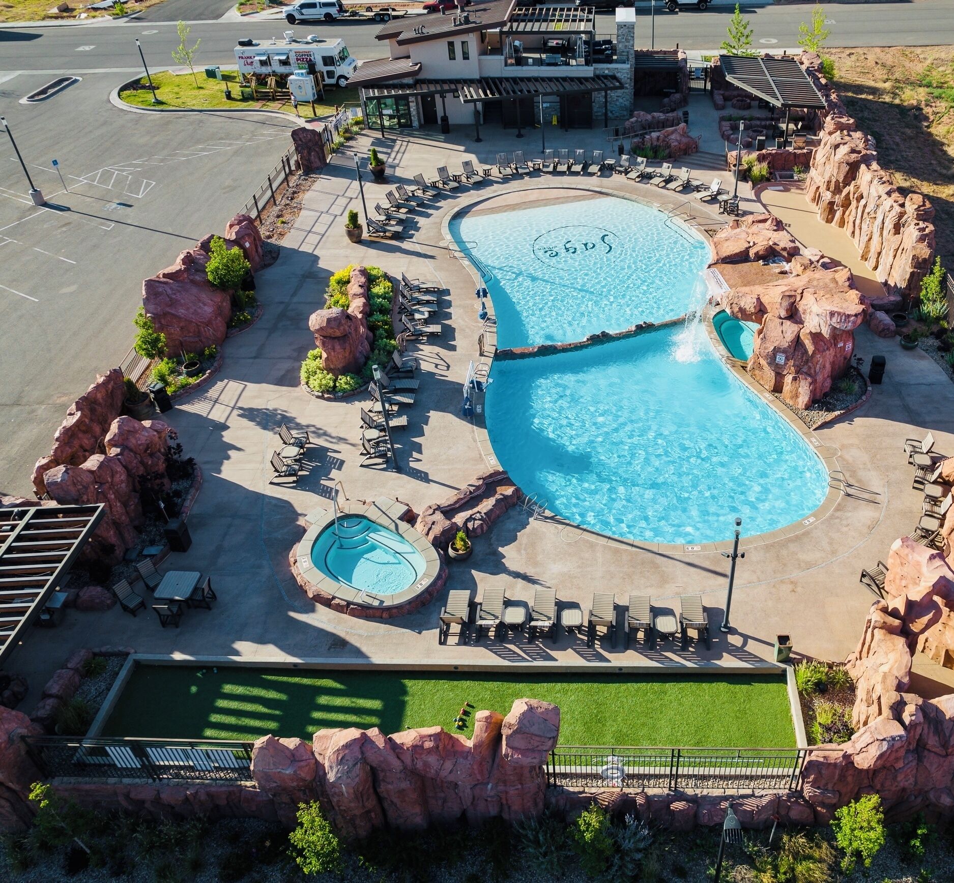 Un resort con dos piscinas amplias, un jacuzzi y un patio con sillas de descanso.