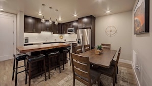 A modern kitchen with dark wood cabinets, stainless steel appliances, and a central island with bar stools. - SageCreek Moab Condo F11 - Stunning Pools/Hot Tubs (Moab)