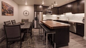 A modern kitchen with dark wood cabinets, stainless steel appliances, and a central island with bar stools.