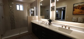 Une salle de bain moderne avec une douche à l’italienne, un grand miroir et un meuble-lavabo.