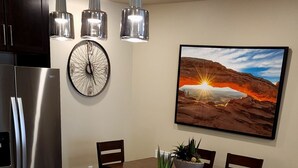 A modern kitchen with a wooden island, stainless steel appliances, pendant lighting, and a scenic wall art piece. - Sage Creek Resort at Moab - Quad Rental F5-6-7-8 (Moab)