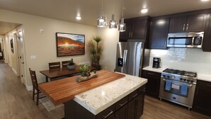 A modern kitchen with dark cabinets, stainless steel appliances, and a wooden island. - Sage Creek Moab "Dual Unit Rental" F6 & F7 (Moab)