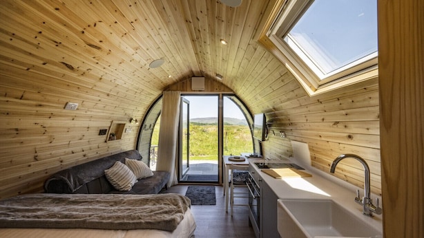 A cozy, wooden interior with a bed, sofa, and kitchenette.