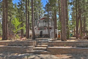 A lodge with a balcony, surrounded by tall trees and a stone staircase leading to the entrance. - Haoles Hideaway I Family Cabin Sleeps 6 (Big Bear)