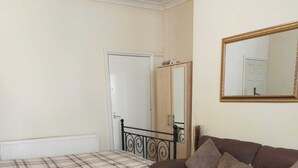 Un dormitorio con una cama, un sofá marrón, una alfombra mullida, un espejo y un radiador.