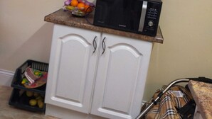 Una cocina con armarios blancos, un microondas en la encimera y un frutero.