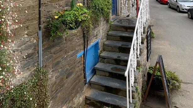 A stone building with a sign reading "Luccer Inn" and a staircase leading to the entrance. - The Lugger Inn (Fowey)