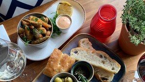 A dining table with various dishes including bread, olives, and a plate with a poached egg. - The Lugger Inn (Fowey)
