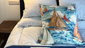 A bedroom with a bed, pillows, and a wall with a nautical-themed mural. - The Lugger Inn (Fowey)