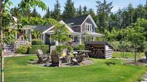 A two-story house with a stone facade, a deck, and a fire pit area with Adirondack chairs. - Seabrook Lost Shaker | Pet Friendly, Hot Tub | 2BR, Sleeps 4, The Croft (Pacific Beach)