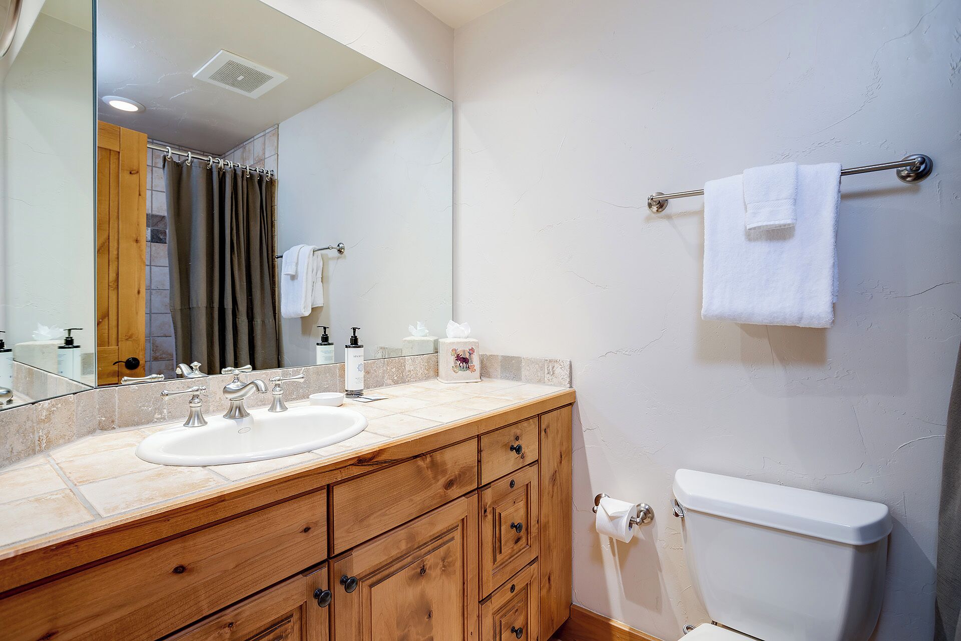 Une salle de bain avec un meuble-lavabo en bois, deux vasques, des toilettes et un porte-serviettes.