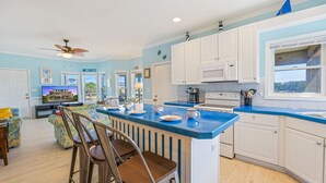 A kitchen with a blue countertop, white cabinets, and a ceiling fan. - Oceanside Home with Hot Tub, Nearby Beach Access, and Grills. A Retreat for All! (Salvo)