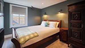 A bedroom with a large bed, a dresser, a window with blinds, and a radiator. - Host & Stay | Fable (Whitby)