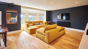 A modern living room with a sofa set, a dining table, and a TV mounted on the wall. - Host & Stay | Fable (Whitby)