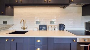 A modern kitchen with dark cabinets, a beige countertop, and a stainless steel range hood. - Host & Stay | Fable (Whitby)