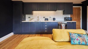 A compact kitchen with dark cabinets, a white countertop, and a small dining area. - Host & Stay | Fable (Whitby)