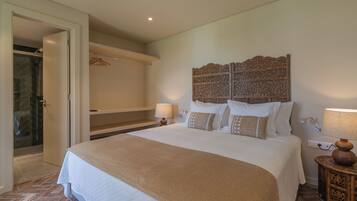 A hotel room with a large bed, a wooden headboard, a bedside table with a lamp, and a shower area.