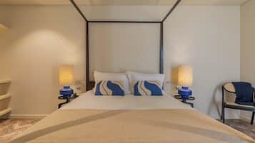 A modern hotel room with a bed, two bedside lamps, a chair, and a small table.