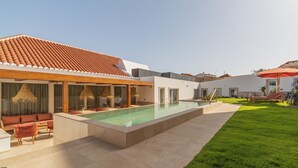 A modern outdoor pool area with a lounge, a covered seating area, and a well-maintained lawn. - Silves History Guest House (Silves)