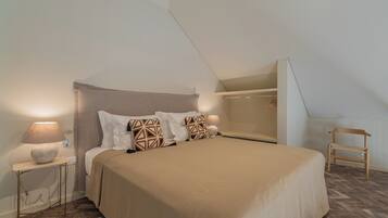Un dormitorio con cama, mesitas de noche, lámpara, una silla y ventana.