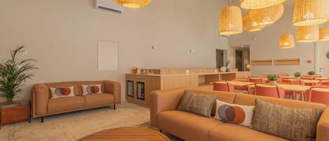 A modern living room with a sofa, coffee table, and dining area with chairs and tables.