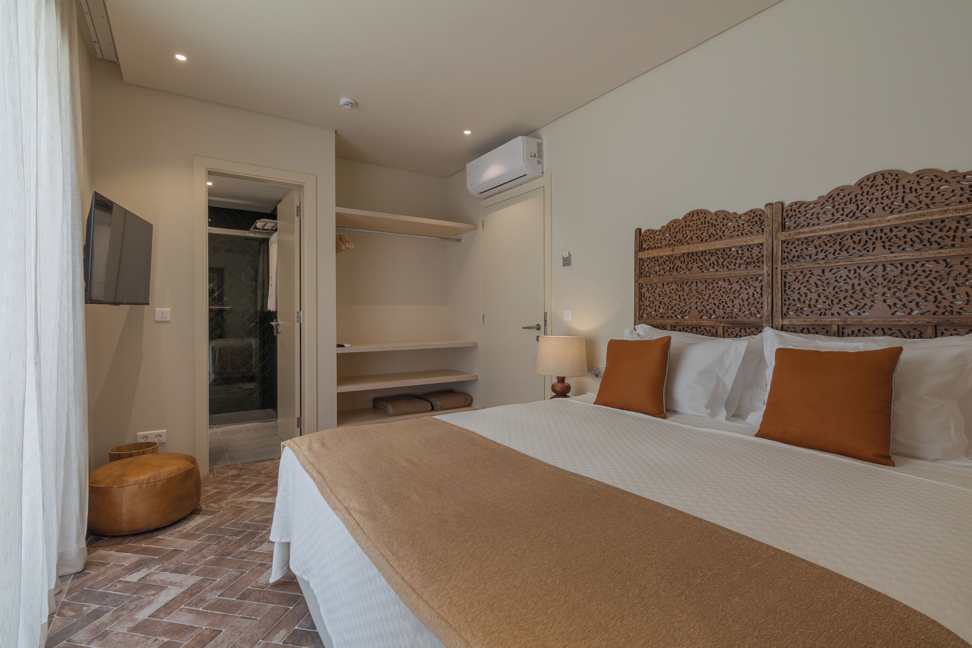 Een hotelkamer met een bed, een televisie, een kledingkast en een douche.