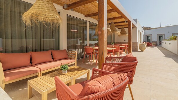 An outdoor seating area with a sofa, chairs, and tables, featuring a thatched ceiling and large windows. - Silves History Guest House (Silves)