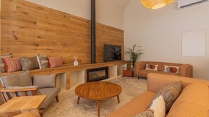 A modern living room with a wooden wall, a fireplace, a sofa set, a coffee table, and two hanging lamps. - Silves History Guest House (Silves)