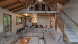 A spacious living area with a large sectional sofa, a wooden coffee table, and a staircase leading to an upper level. - Bear Hug Hideaway by Innsbrook Vacations! (Innsbrook)