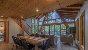 A spacious loft-style room with a wooden ceiling, large windows, a dining area with a table and chairs, and a cozy seating area with a sofa and armchairs. - Bear Hug Hideaway by Innsbrook Vacations! (Innsbrook)