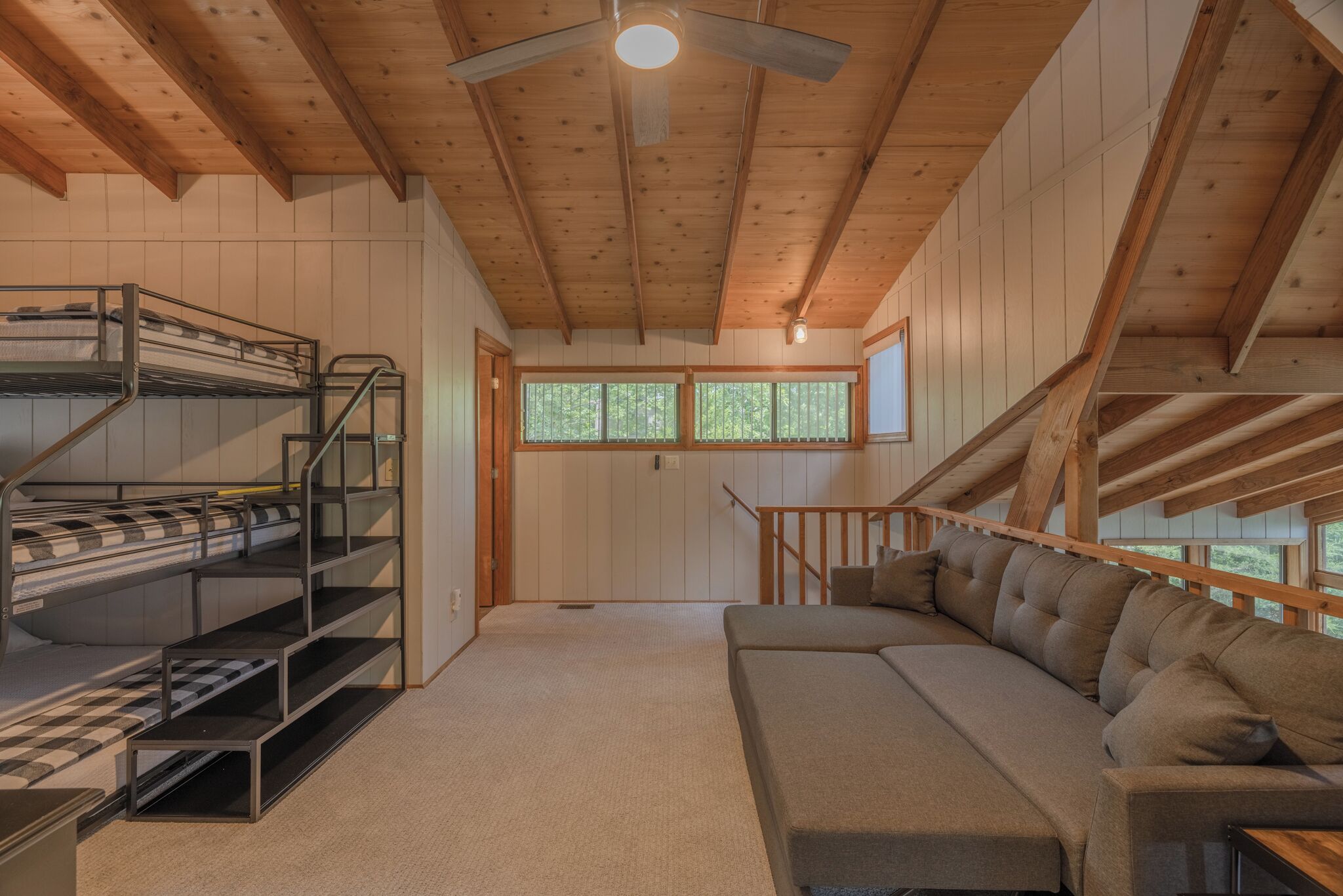 A cozy cabin with a bunk bed, a sofa, and a ceiling fan.