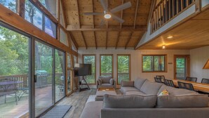 A spacious living area with a large gray sofa, a television, and a dining table. - Bear Hug Hideaway by Innsbrook Vacations! (Innsbrook)