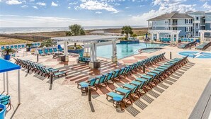 Zona junto a la piscina con sillones de descanso y una piscina, con vistas a la playa.
