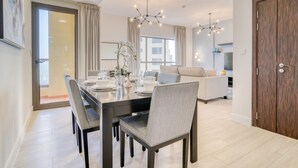 A modern dining area with a dark wooden table and chairs, a chandelier, and a view of the living room in the background. - High Floor 2BR w/ a View of the Dubai Marina,Near fr. the Beach , Shams 1, JBR (Dubai)