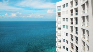 Un hotel moderno con múltiples balcones con vistas a un mar azul y despejado.