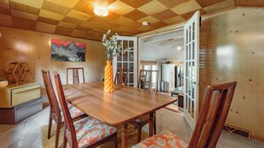 A wooden dining table with chairs, a vase with flowers, and a painting on the wall. - Dog Friendly Cottage w/ Dock & Shuffleboard (Swanton)