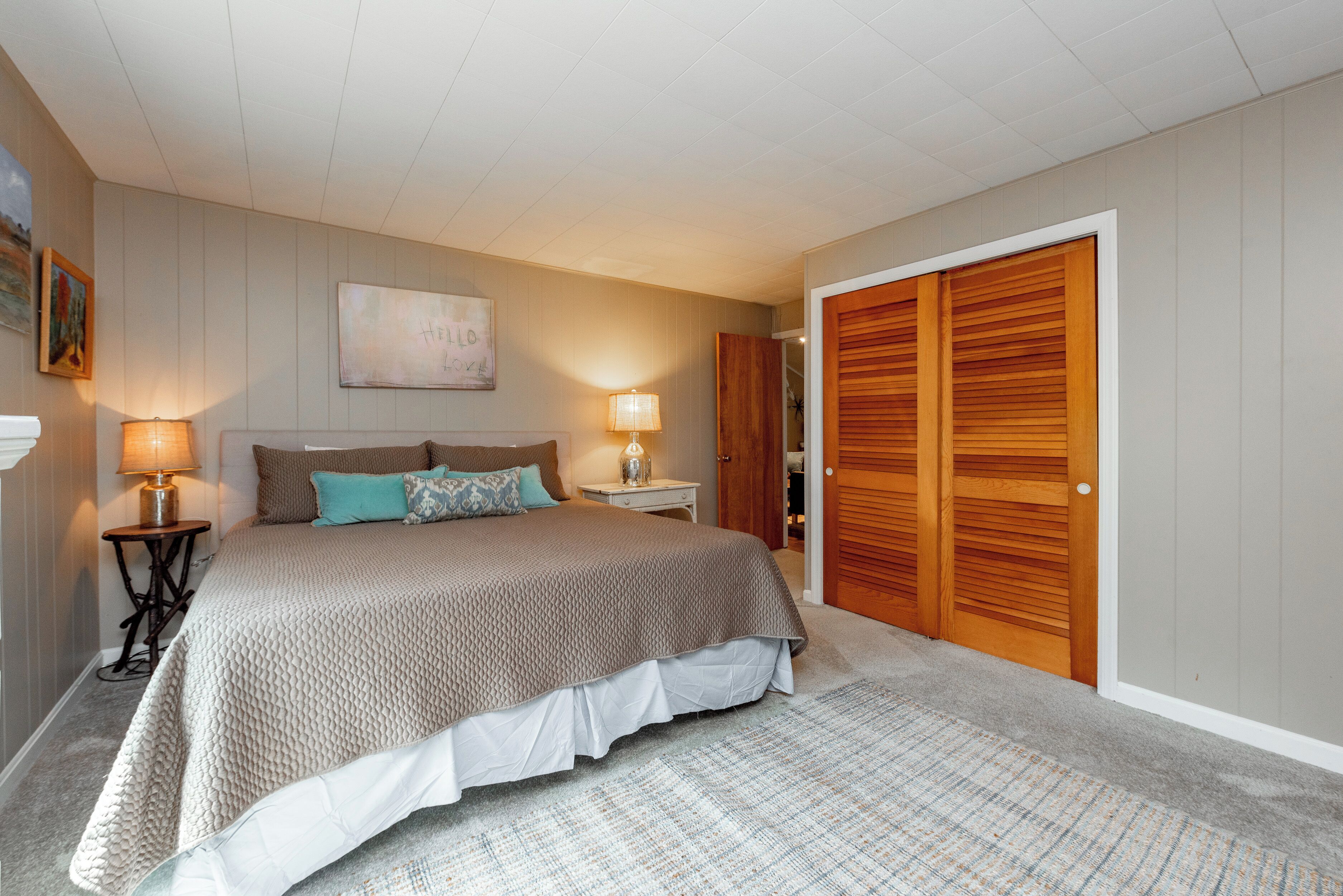 Une chambre à coucher avec un lit, des lampes de chevet, une table de chevet, une armoire en bois et un tableau au mur.