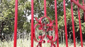 A red metal fence with decorative spikes and a circular ornamental piece. - Maison au Calme Avec Jardin, Terrasse et Barbecue (Dampierre-sur-Boutonne)