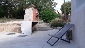 A brick oven structure with steps leading up to it, surrounded by gravel and greenery. - Maison au Calme Avec Jardin, Terrasse et Barbecue (Dampierre-sur-Boutonne)