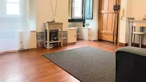 Une pièce avec un plancher en bois, un téléviseur à écran plat fixé au mur, une porte en bois et une petite table sur laquelle est posée une plante.