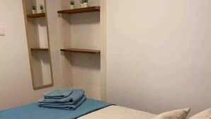 Une chambre à coucher avec un lit, un miroir et des étagères ornées de plantes.