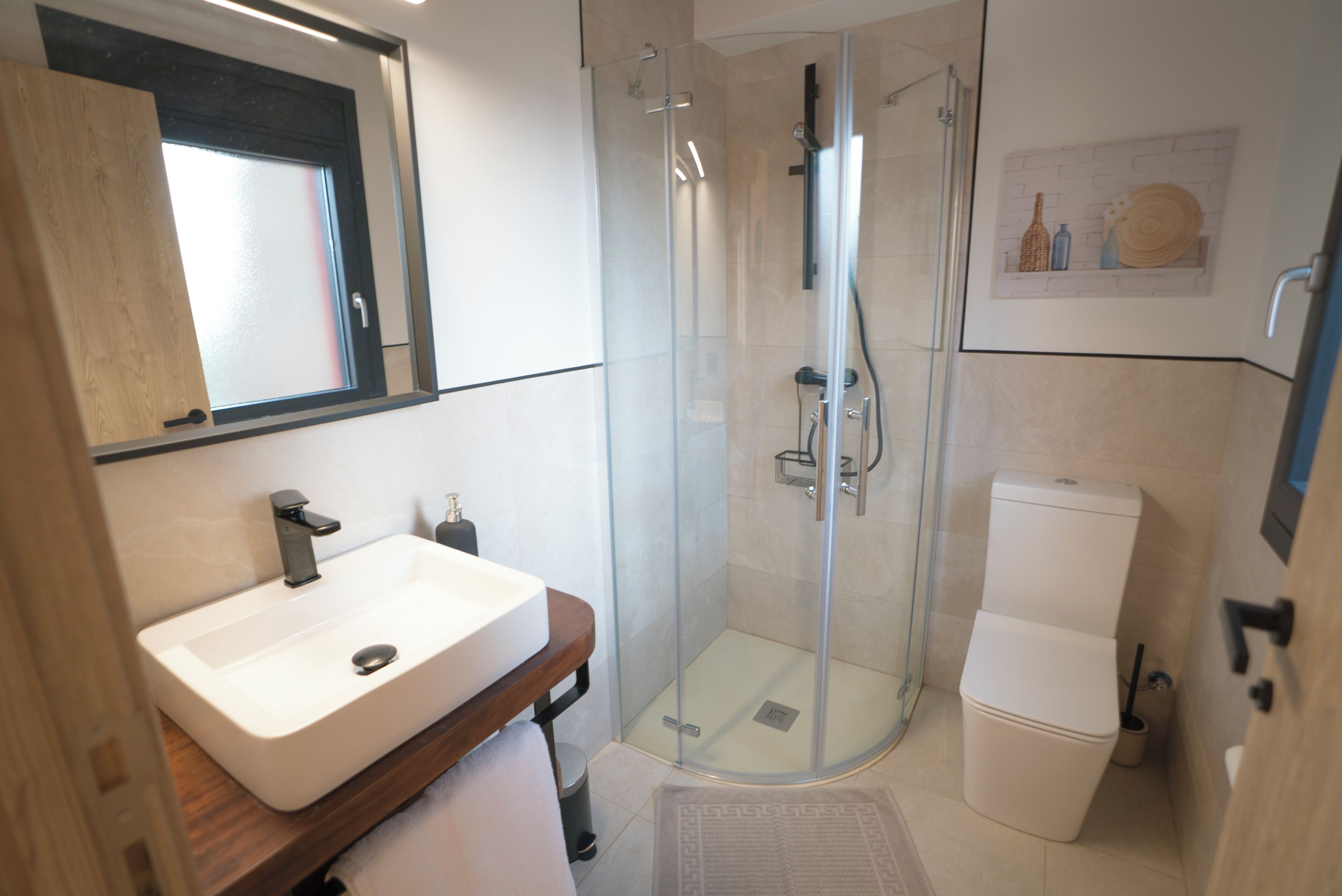 A modern bathroom with a glass-enclosed shower, a white sink, and a toilet.