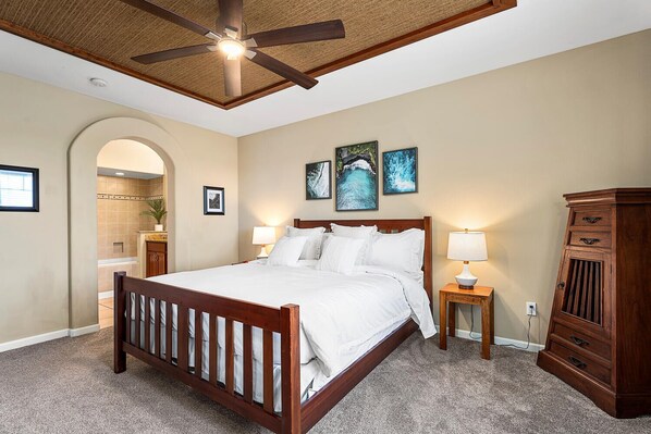 A bedroom with a wooden bed, two bedside lamps, a ceiling fan, and a wooden cabinet.