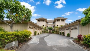 A residential building with a central entrance, multiple garages, and a landscaped driveway.