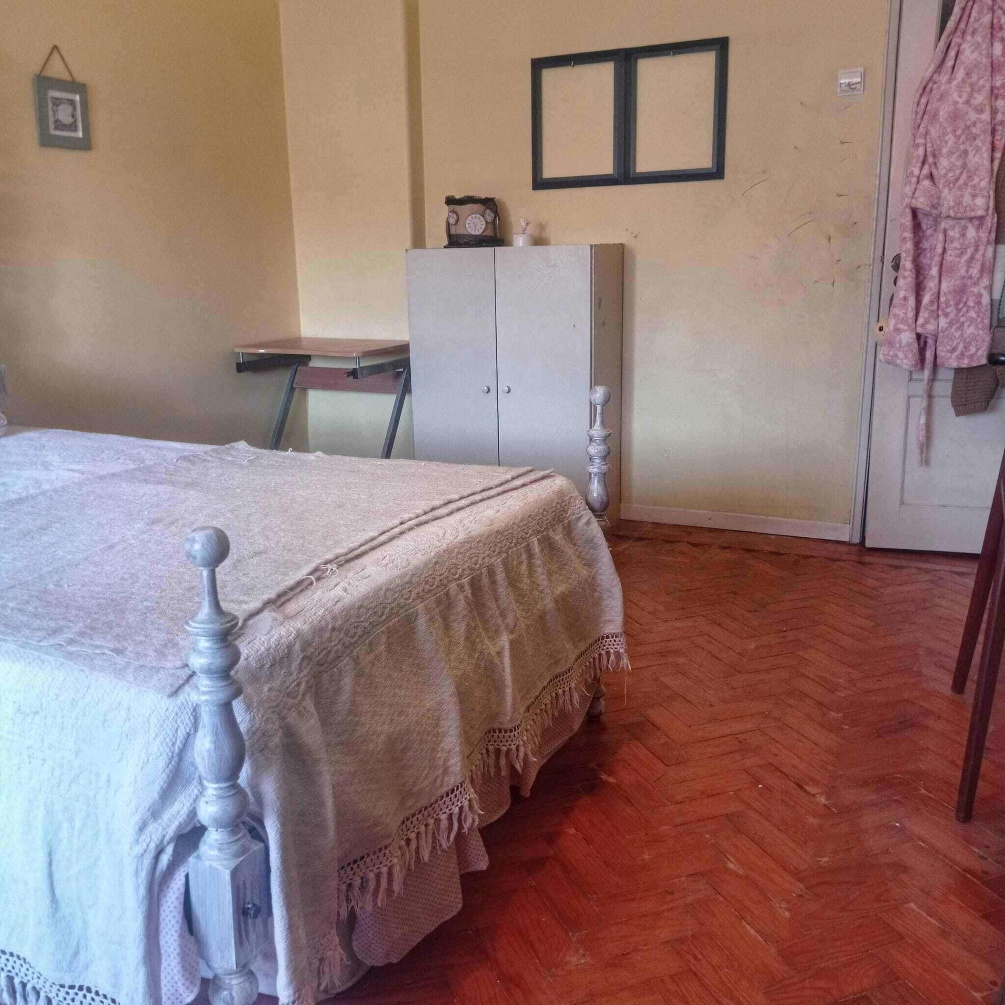 Un dormitorio con una cama de madera, un armario, una mesita y una silla.