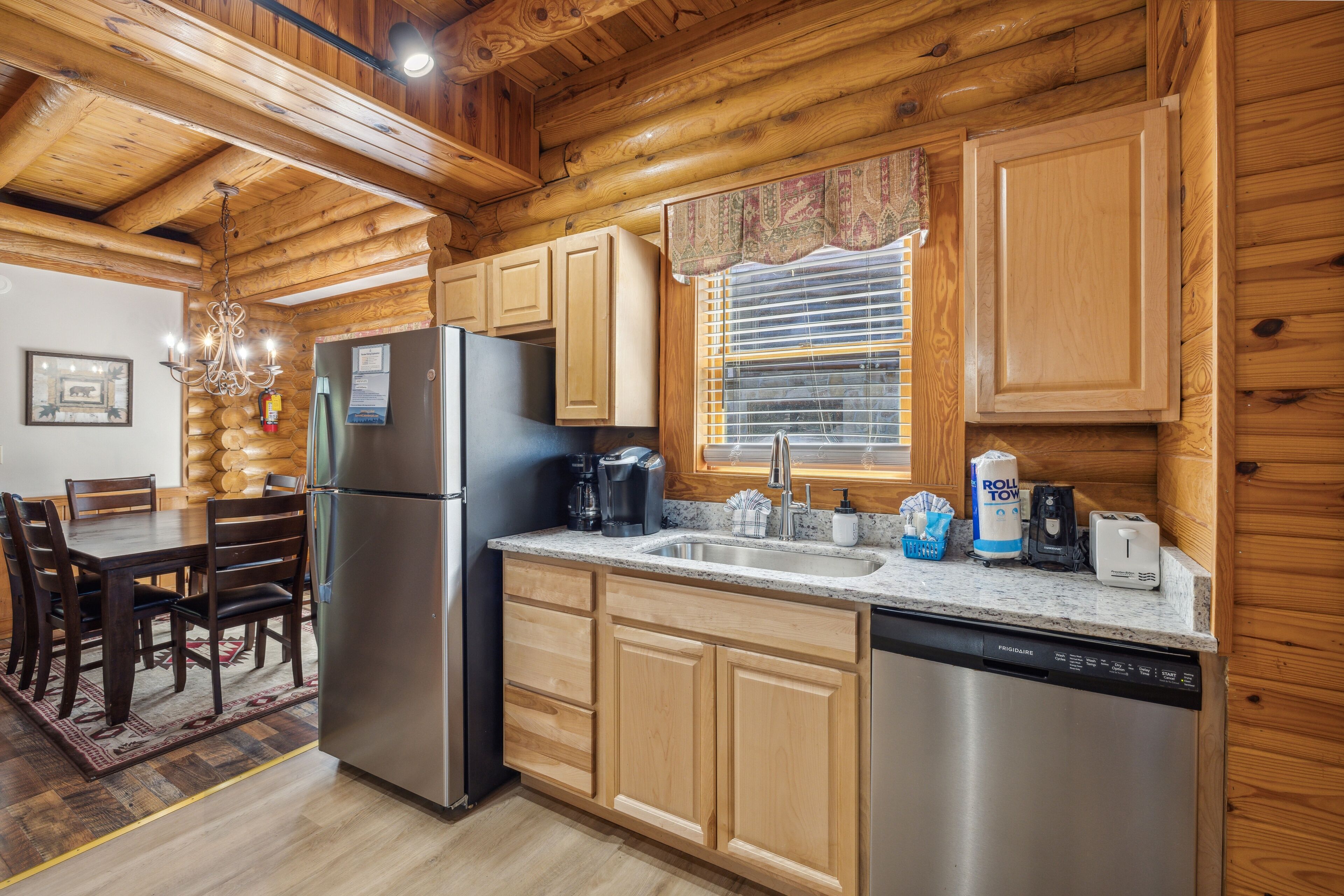 A wooden cabin kitchen with a refrigerator, stove, sink, and wooden cabinets.