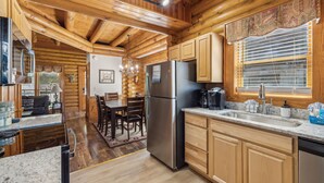 A log cabin interior with a kitchen, dining area, and living room. - Golf View 2 Bedroom Cabin by RedAwning (Pigeon Forge)