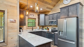 A modern kitchen with granite countertops, stainless steel appliances, and wooden cabinetry. - Antler Ridge 3 Bedroom Cabin by RedAwning (Sevierville)